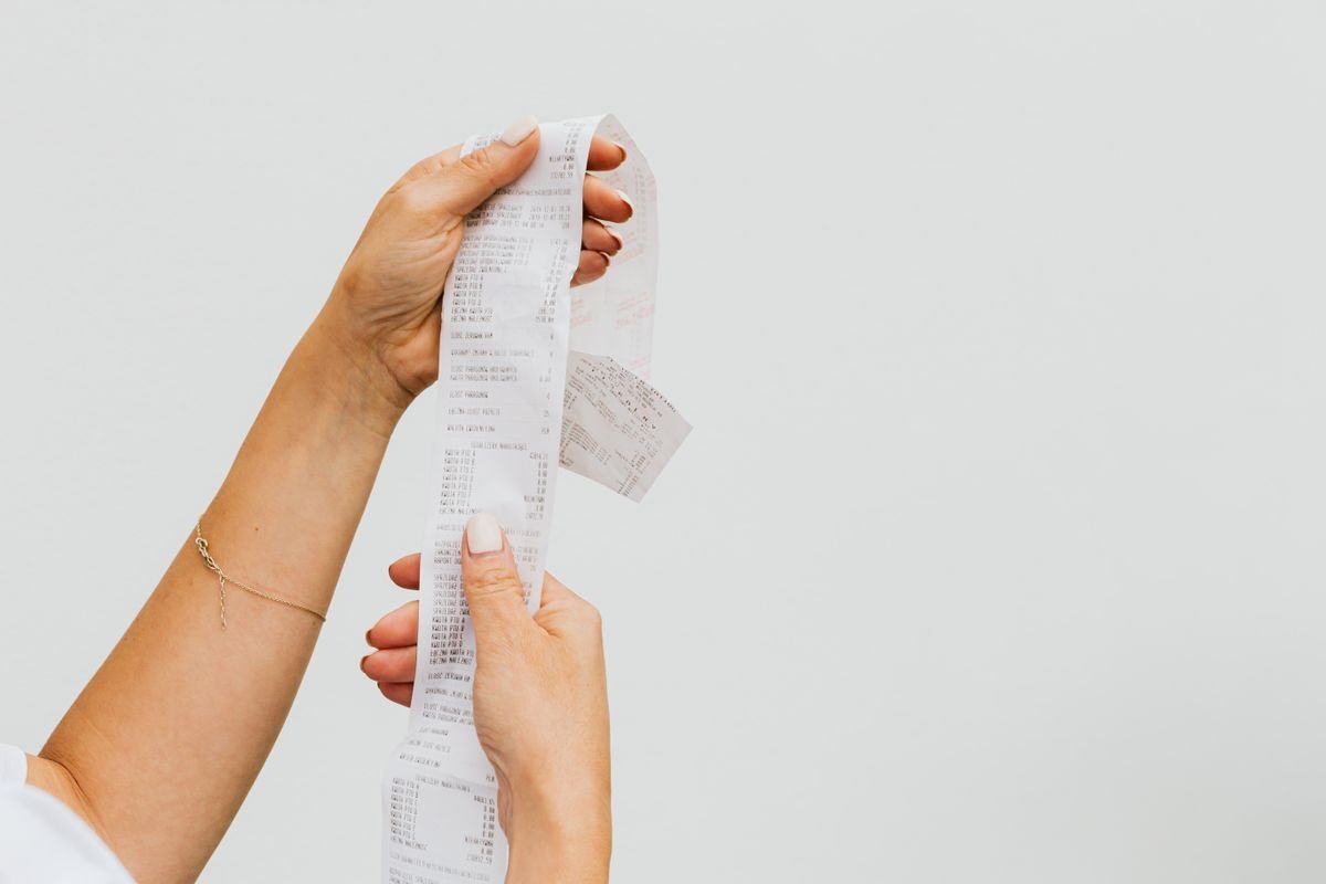 Hands holding a very long printed receipt